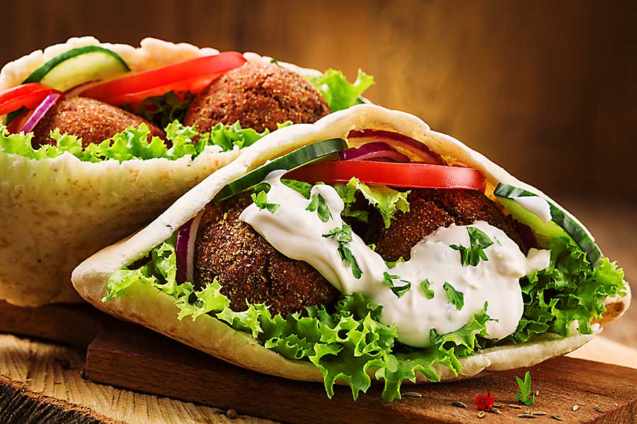Israeli Falafel and fresh vegetables in pita bread on wooden table