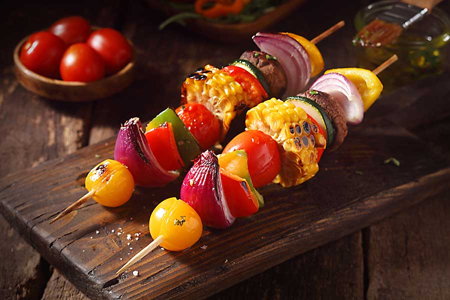 Colourful vegetarian vegetable skewers with fresh roasted or grilled sweet peppers, onion, mushroom, corn, eggplant and cherry tomatoes.