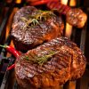 Charcoal bbq experience, red chilli peppers and grass-fed hormon free beef rump steak on the grill with garlic and rosemary