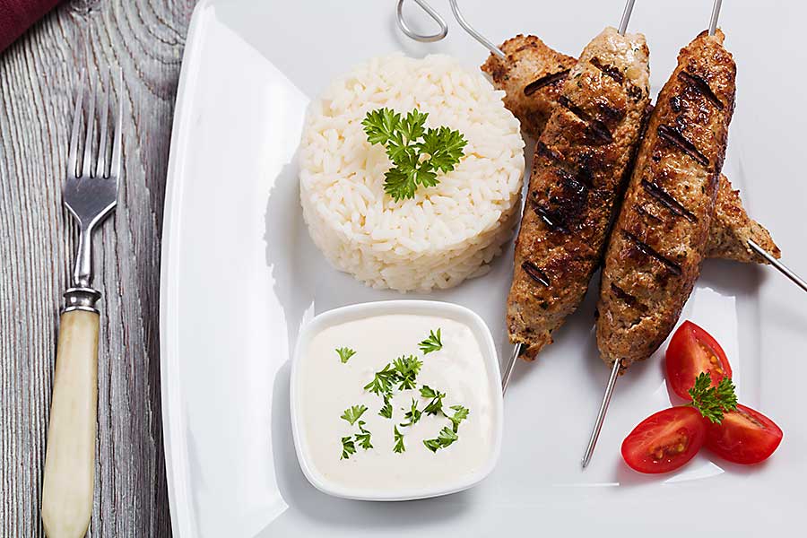 Barbecued kofta - kebeb with rice and vegetables on a plate.