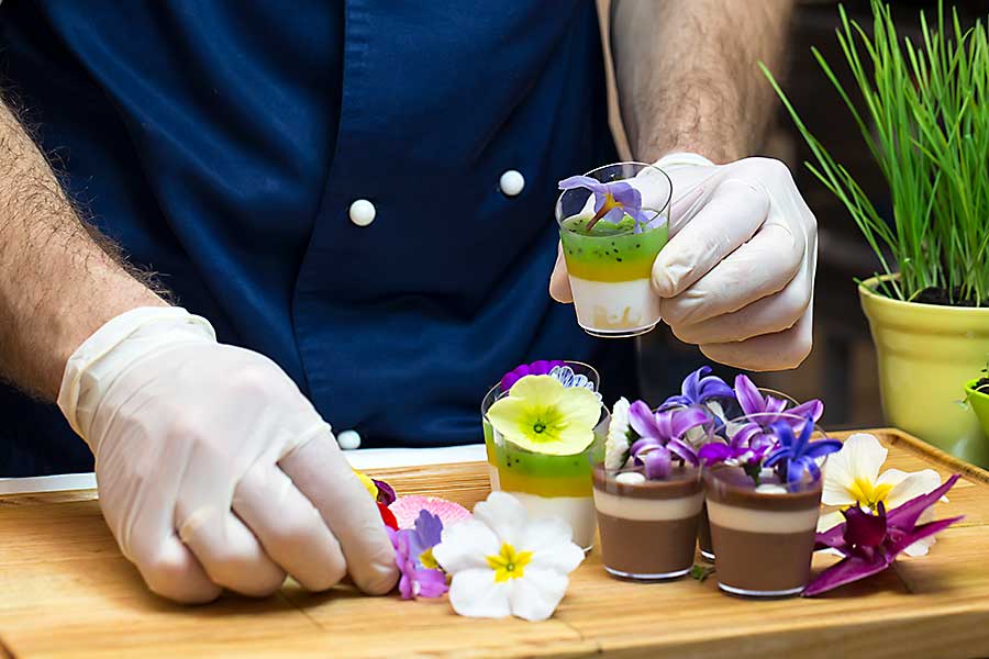 Chef prepares canapes dessert edible flowers and buds