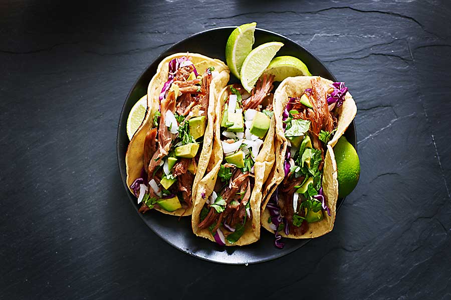 Mexican street tacos with pork carnitas, avocado, onion, cilantro, and red cabbage