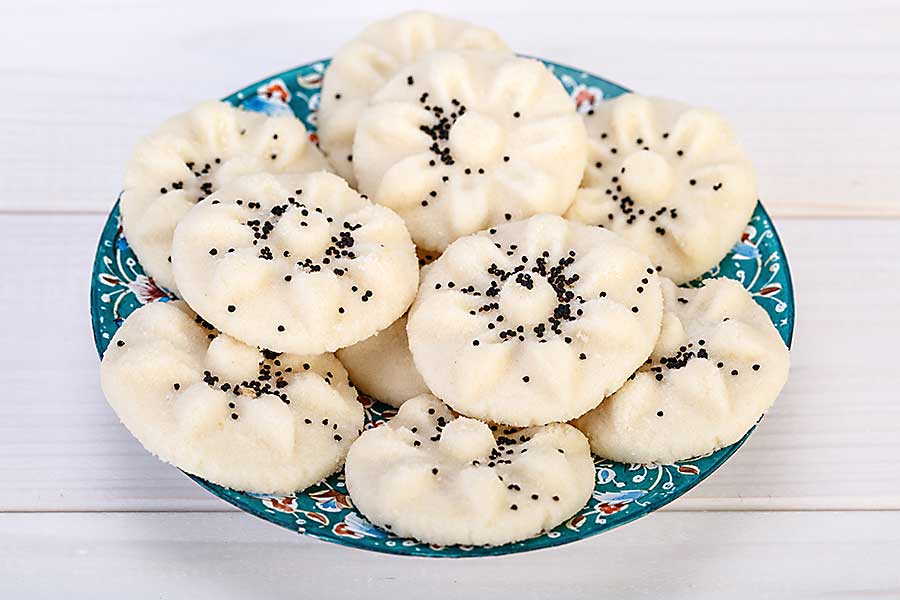 Flower shaped Persian sweet rice cookies Naan Berenji with Poppy Seeds in a traditional design turquoise plate