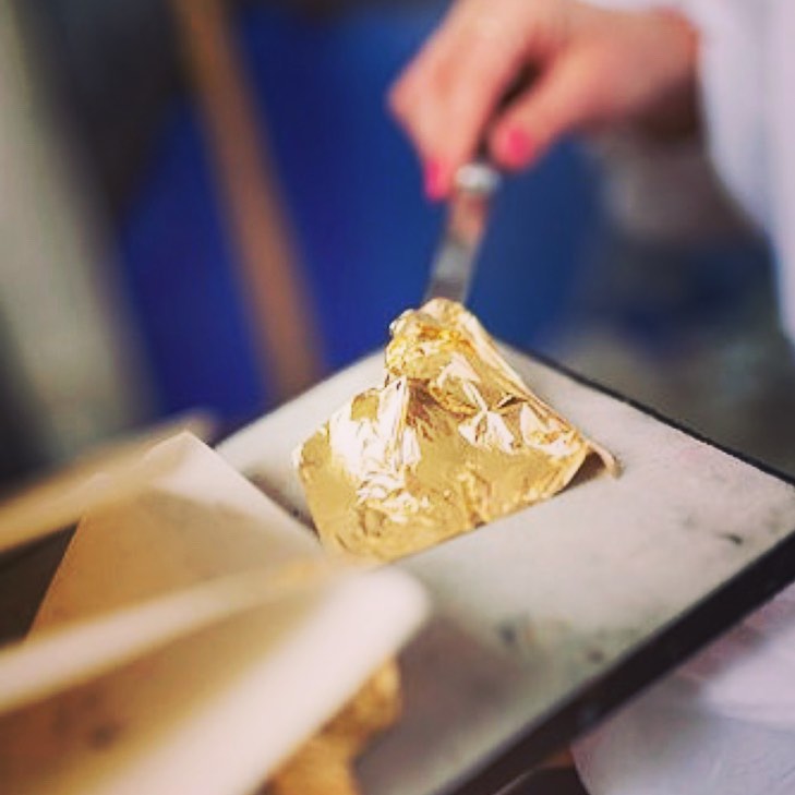 a female hand is taking a piece of gold leaf out from a plate