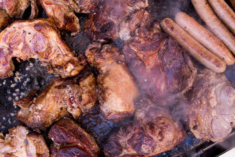 Assorted grilled meats and sausages cooking on a smoky barbecue