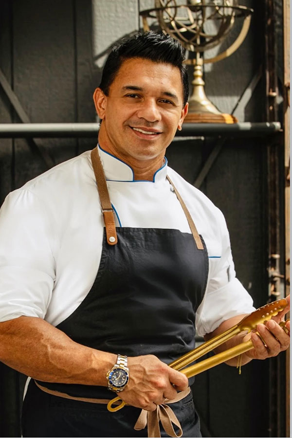 Chef Jean Pierre Palacio Profile holding golden tongs